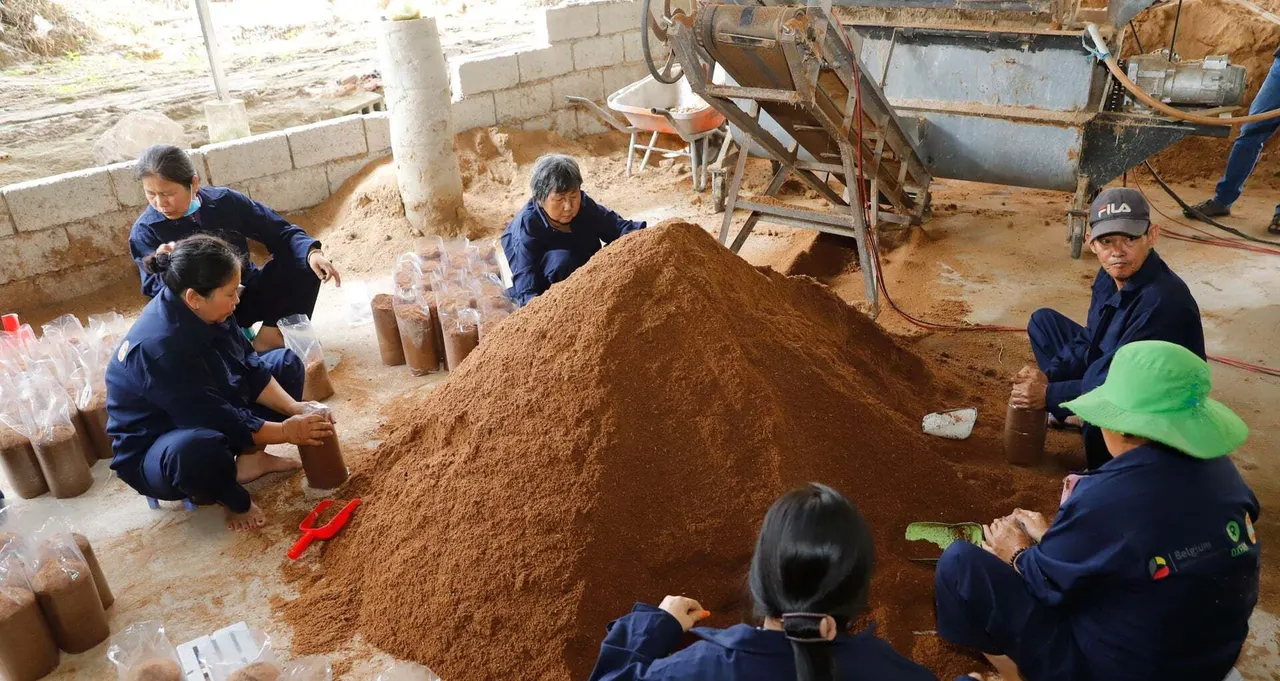 Công nhân mặc đồng phục xanh ngồi quanh đống giá thể, đóng giá thể vào bịch